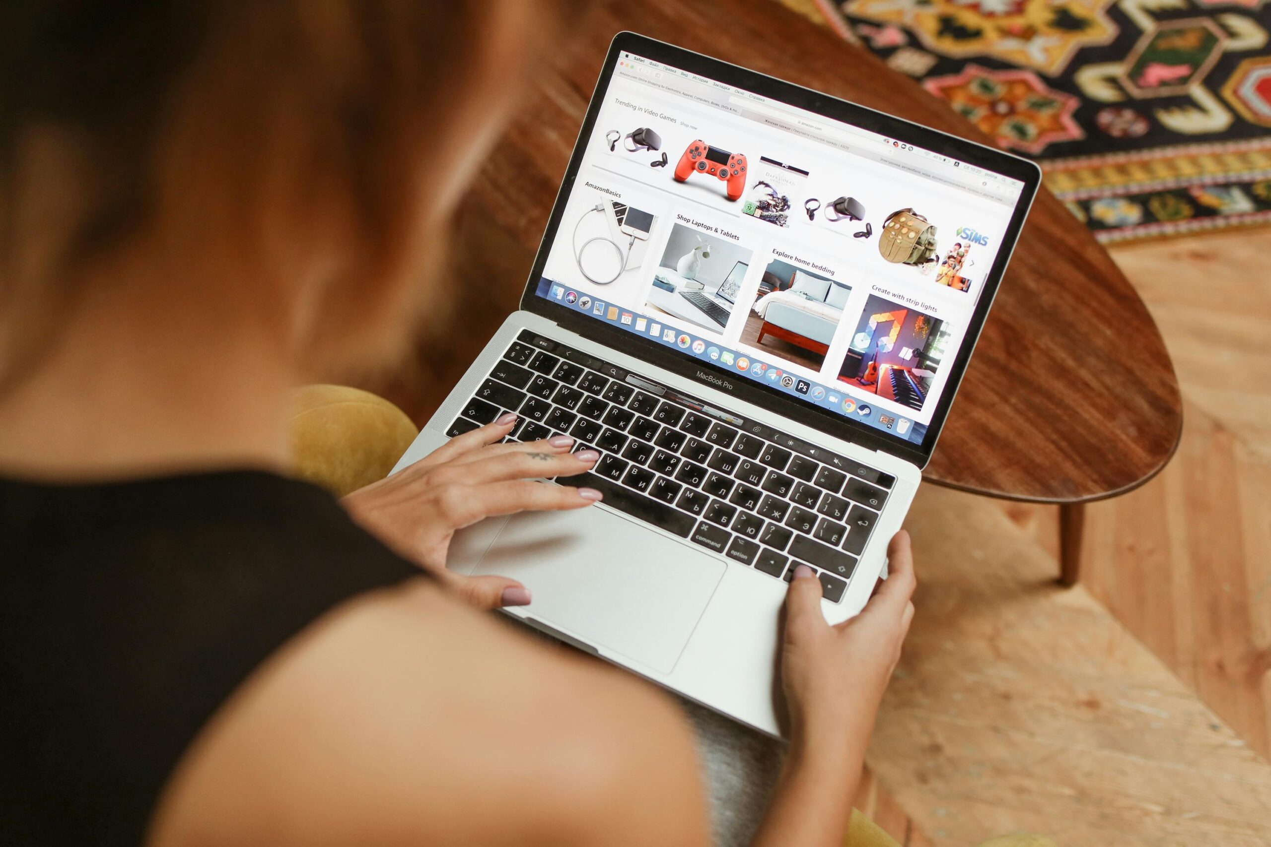 A woman shops online on her laptop while seated in a cozy home environment.